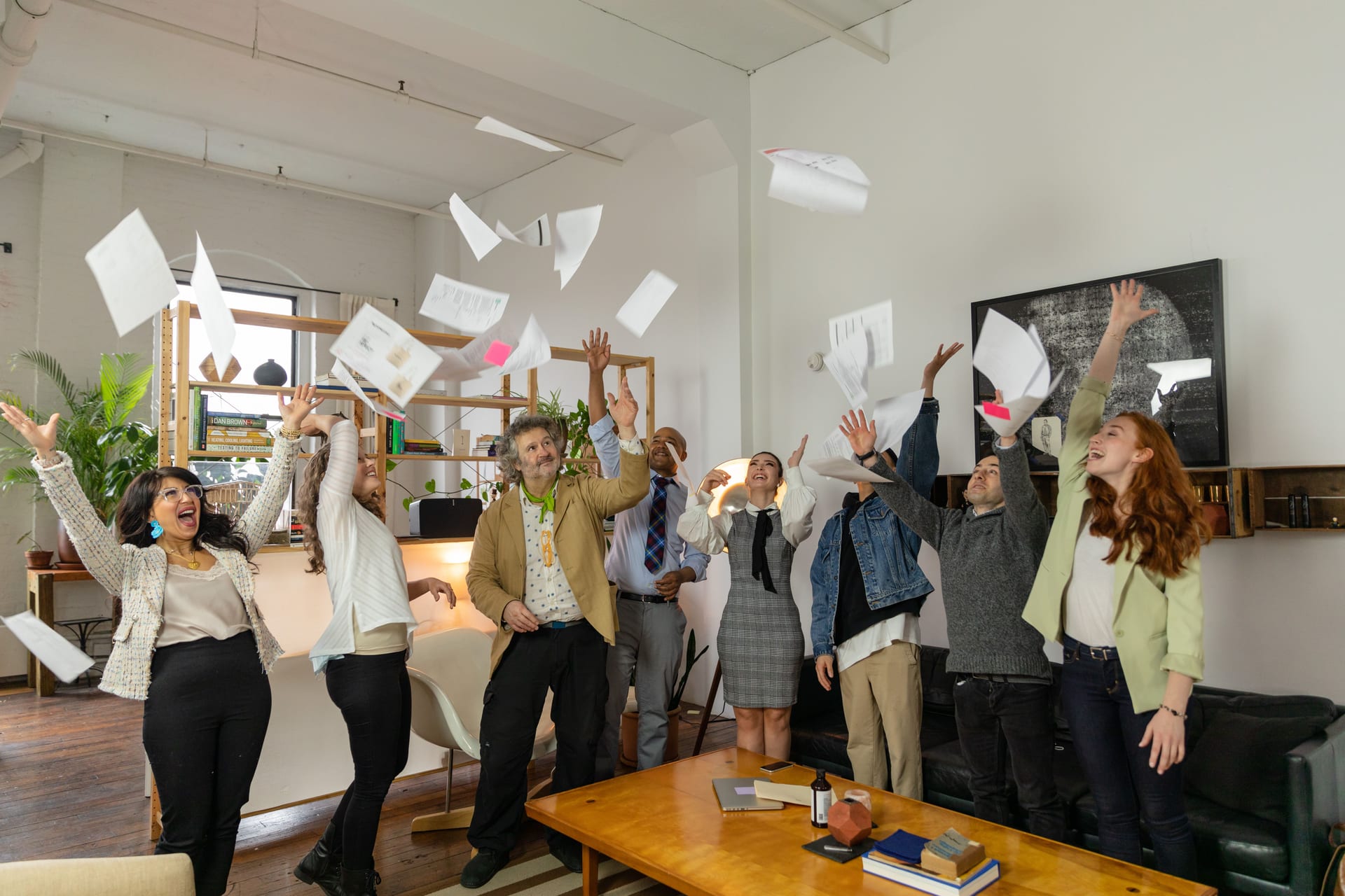 A team in an office throwing sheets of paper into the air