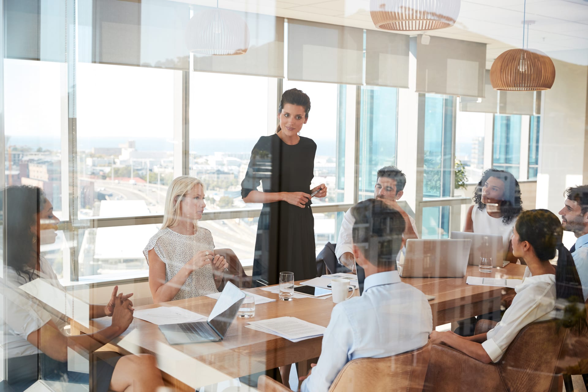 A woman standing to address colleagues seated around a boardroom table